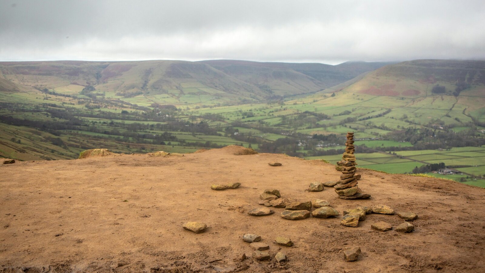Green farmland with a dry stone wall in the Peak District